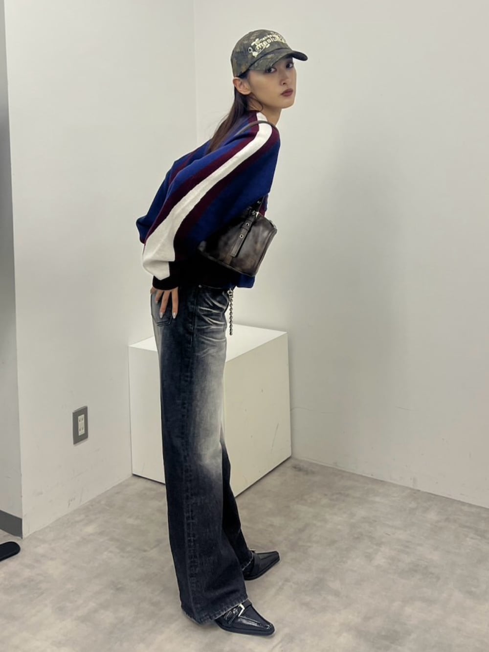 ブラック系のデニムパンツ、ブラウン系のショルダーバッグ、レッド系のニット/セーターを着用したレディースの冬コーディネートの2枚目の写真