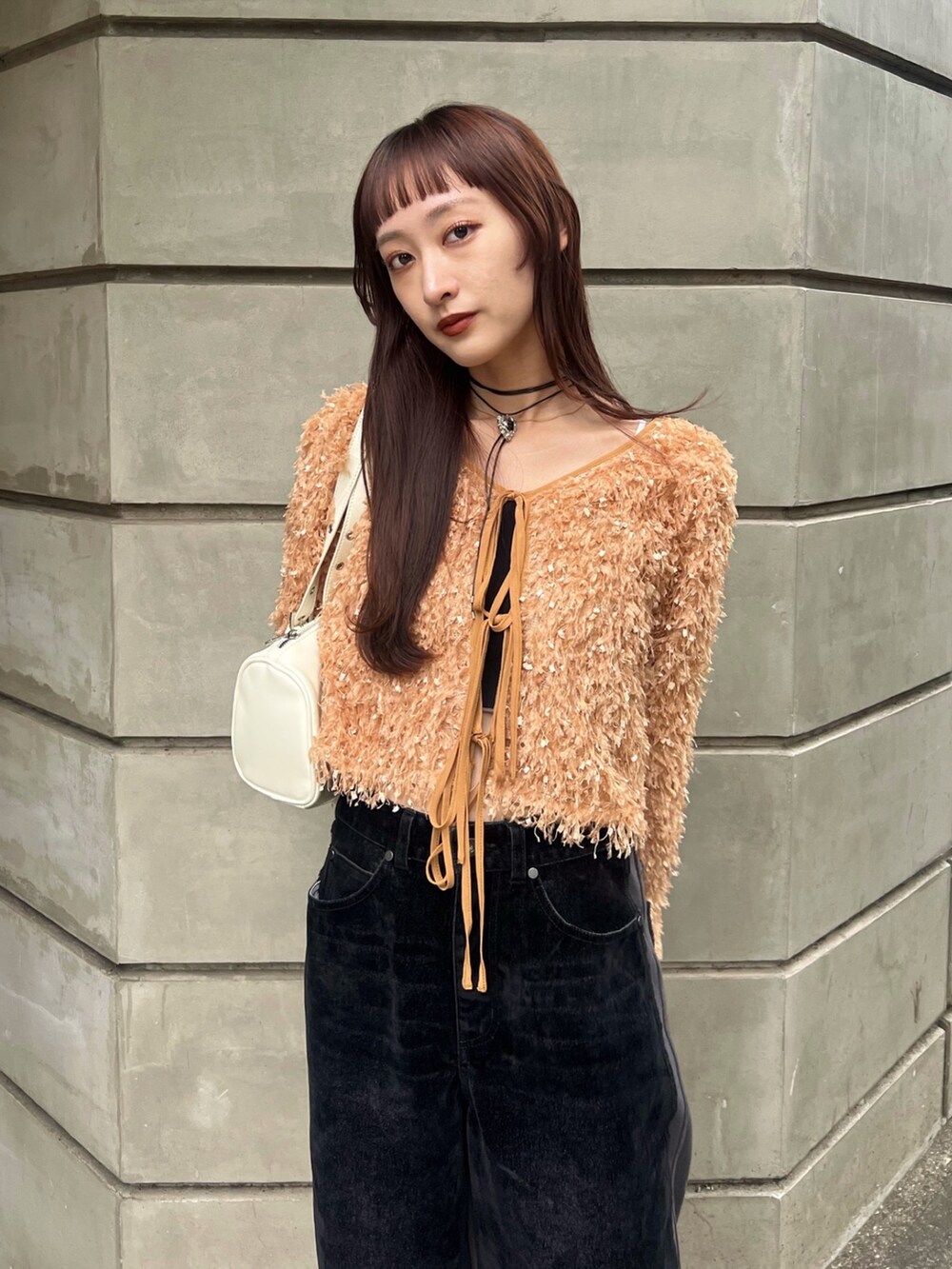 ブラック系のデニムパンツ、ホワイト系のショルダーバッグ、ベージュ系のカーディガン/ボレロを着用したレディースの冬コーディネートの3枚目の写真