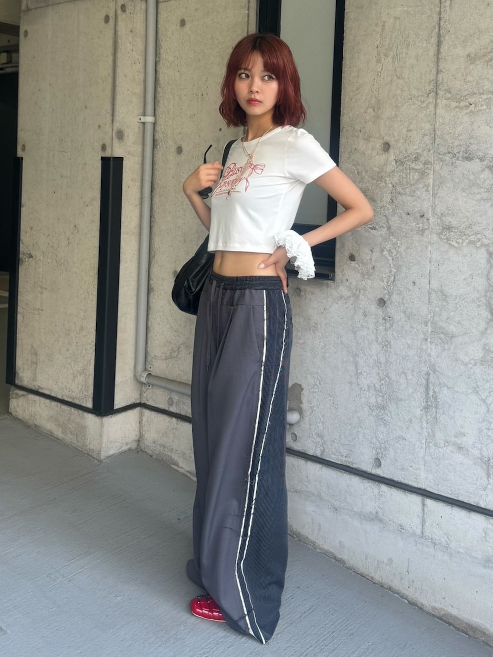 ホワイト系のTシャツ/カットソー、グレー系のスラックス、レッド系のサンダルを着用したレディースの夏コーディネートの3枚目の写真