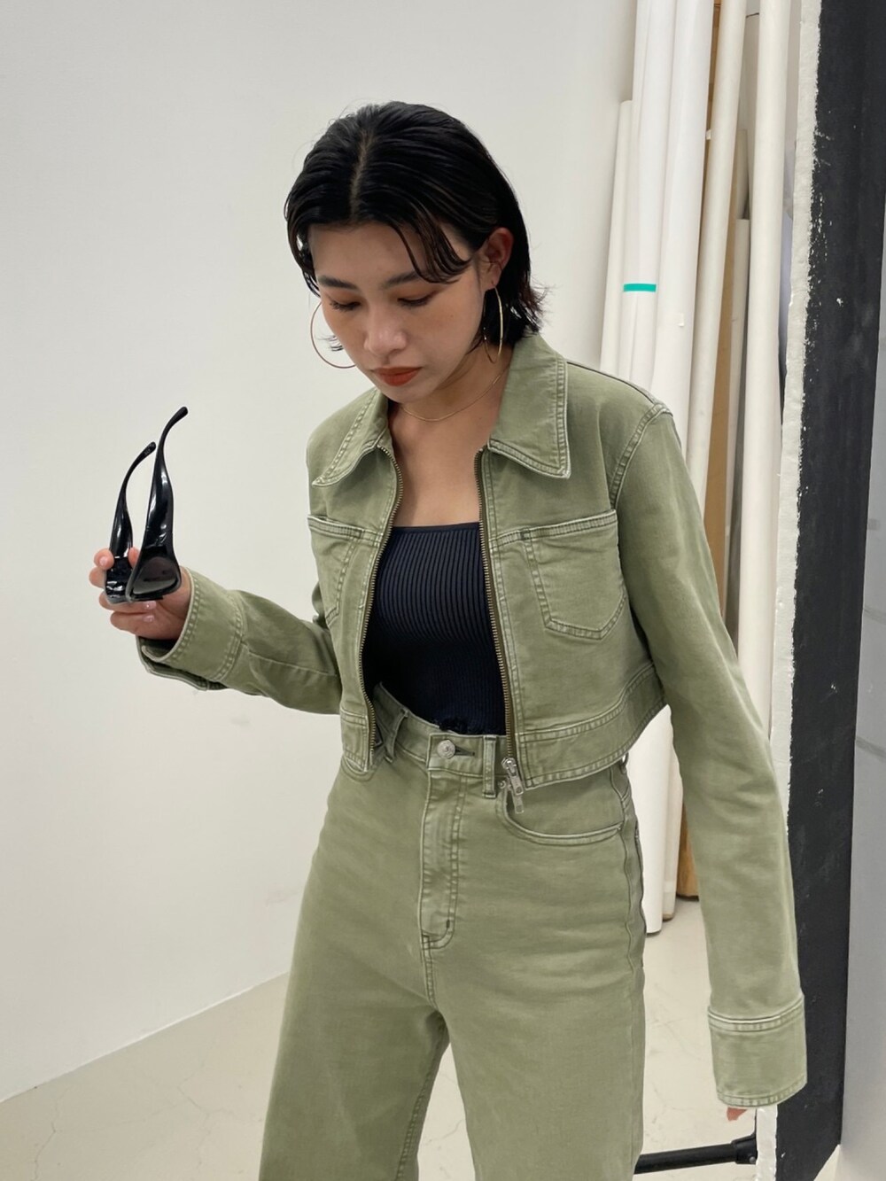 ブラック系のニット/セーター、グリーン系のデニムジャケット、グリーン系のデニムパンツを着用したレディースの夏コーディネートの3枚目の写真