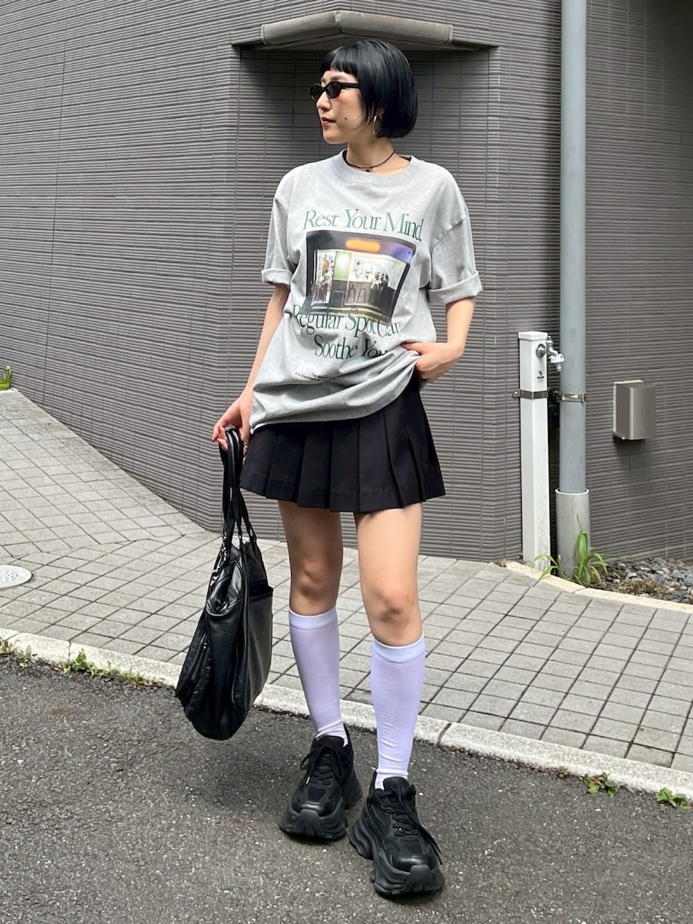 グレー系のTシャツ/カットソー、ブラック系のスカート、ブラック系のスニーカーを着用したレディースの夏コーディネートの2枚目の写真