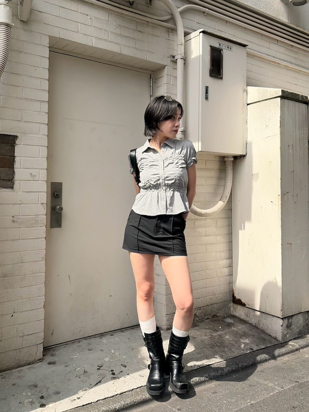 グレー系のTシャツ/カットソー、ブラック系のスラックス、ブラック系のブーツを着用したレディースの夏コーディネートの2枚目の写真