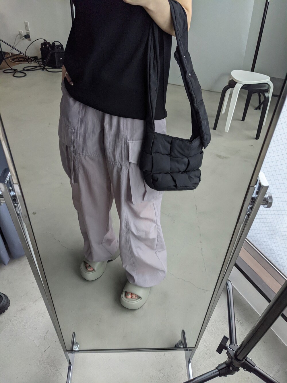 ブラック系のショルダーバッグ、ブラック系のニット/セーター、パープル系のスラックスを着用したレディースの春コーディネートの5枚目の写真