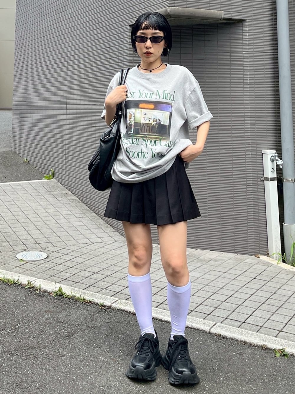 グレー系のTシャツ/カットソー、ブラック系のスカート、ブラック系のスニーカーを着用したレディースの夏コーディネートの3枚目の写真