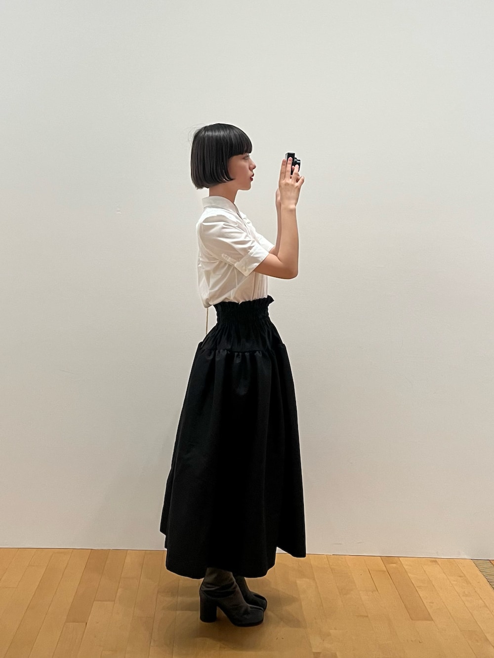 ホワイト系のシャツ/ブラウス、ブラック系のスカート、ブラック系のブーツを着用したレディースの夏コーディネートの2枚目の写真