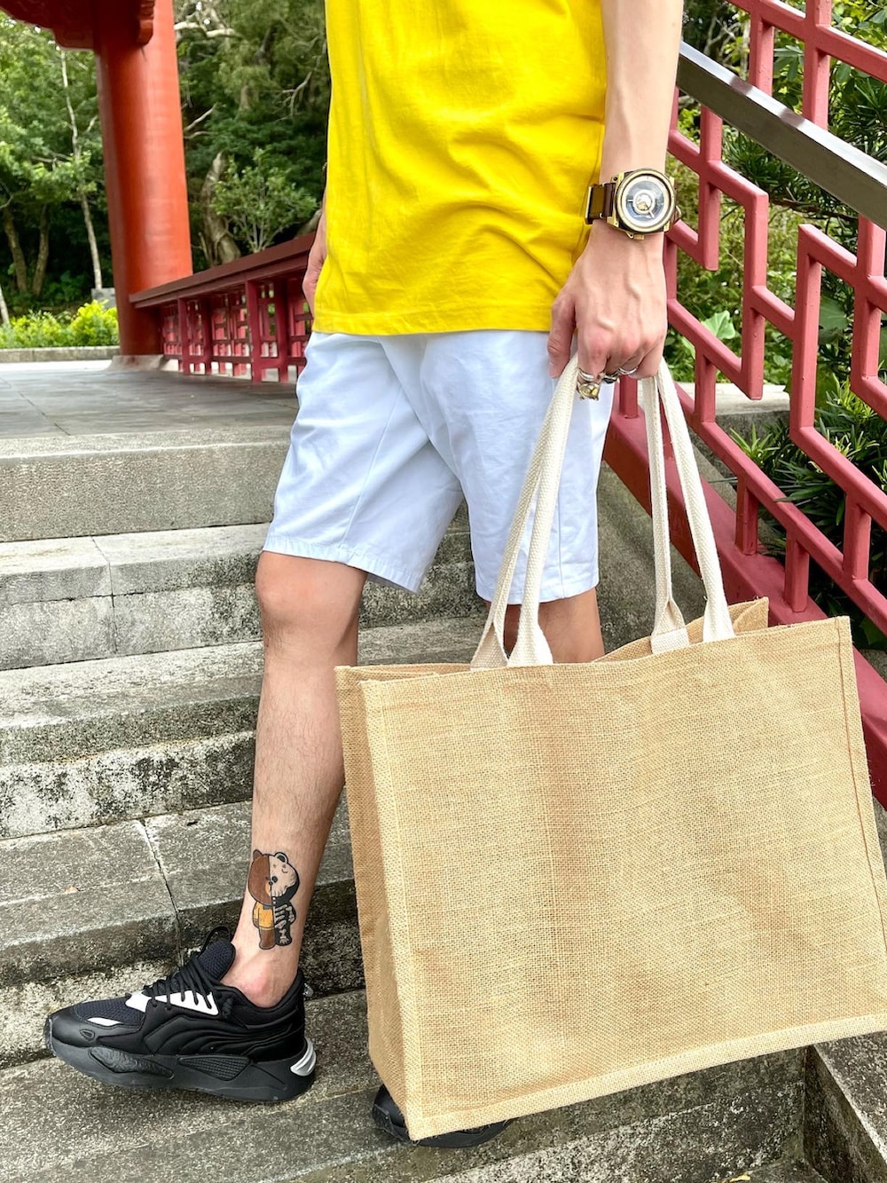 イエロー系のTシャツ/カットソー、ホワイト系のチノパンツ、ベージュ系のトートバッグを着用したメンズの夏コーディネートの2枚目の写真