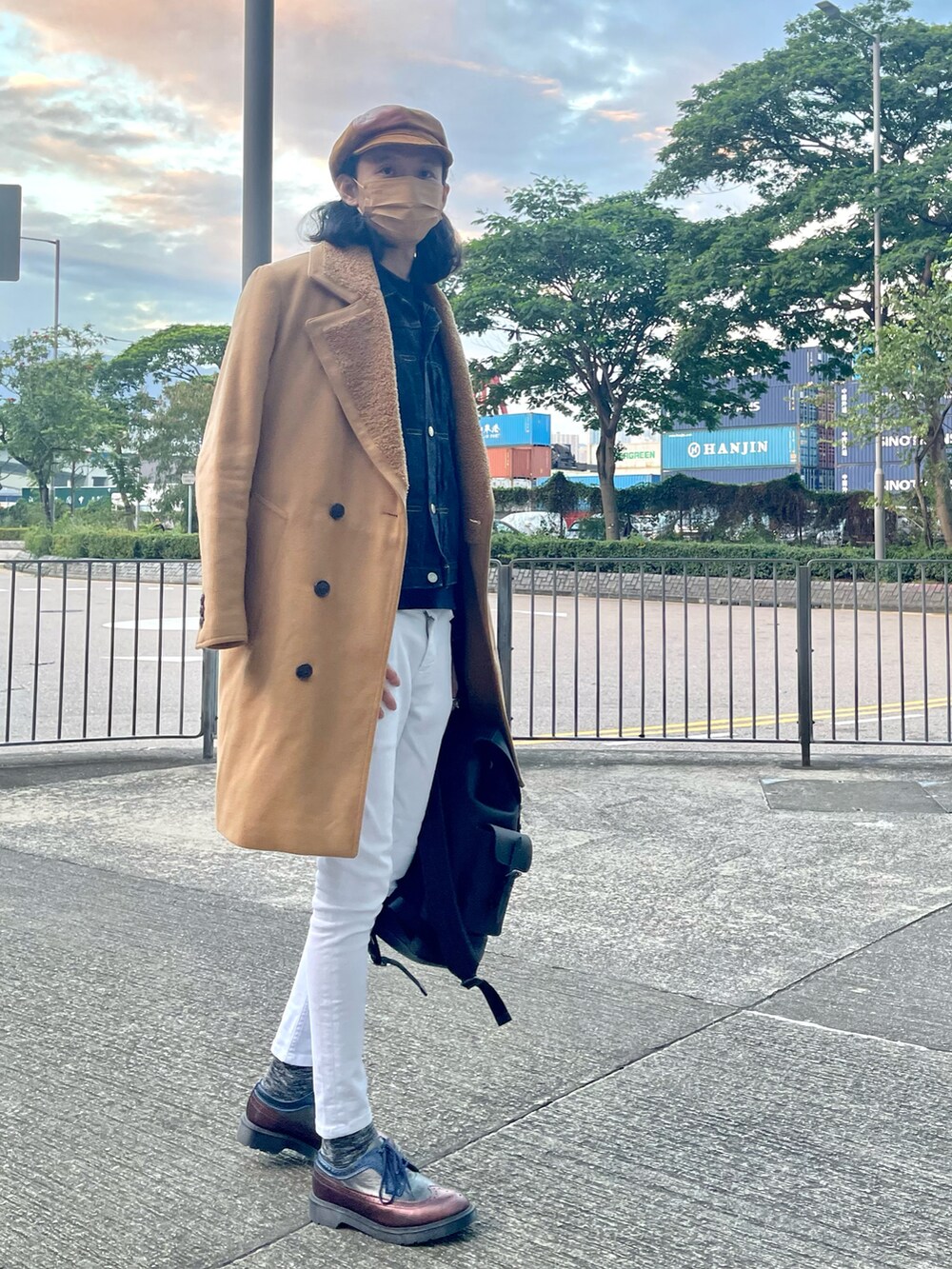 ブラウン系のチェスターコート、ブルー系のデニムジャケット、ブラック系のバックパック/リュックを着用したメンズの春コーディネートの2枚目の写真