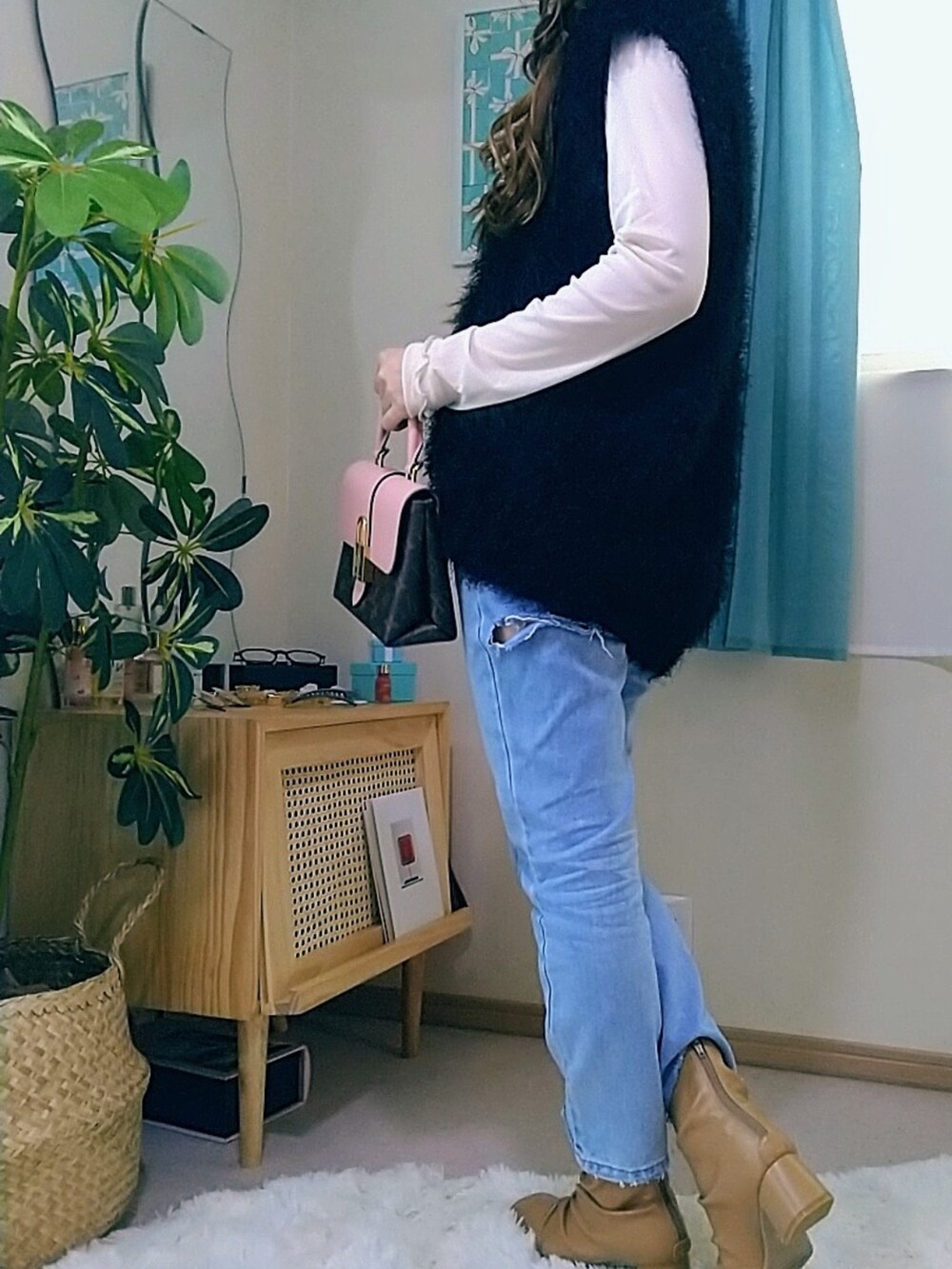 ブルー系のデニムパンツ、ブラック系のベスト、ベージュ系のブーツを着用したレディースの春コーディネートの3枚目の写真