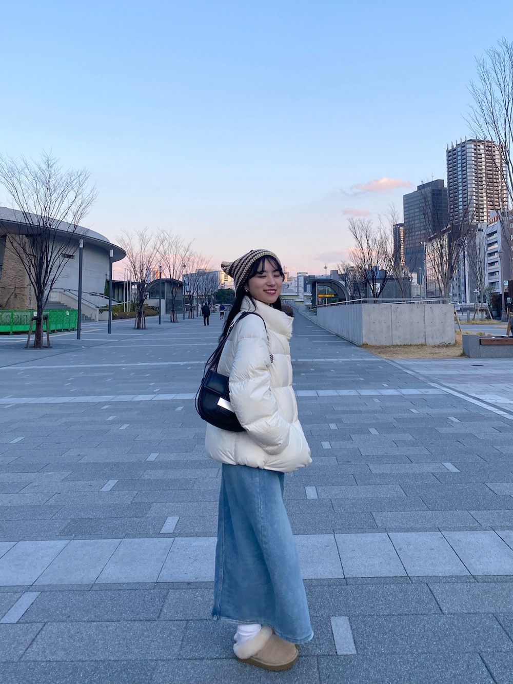 ホワイト系のダウンジャケット/コート、ブルー系のデニムスカート、ベージュ系のサンダルを着用したレディースの冬コーディネートの3枚目の写真