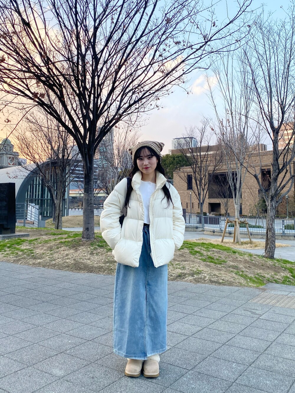 ホワイト系のダウンジャケット/コート、ブルー系のデニムスカート、ベージュ系のサンダルを着用したレディースの冬コーディネートの2枚目の写真