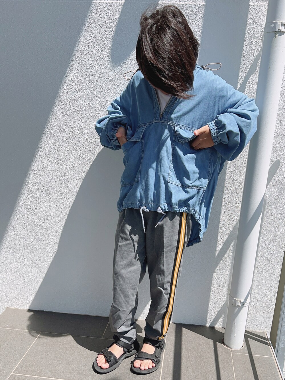 グレー系のスラックス、ブルー系のデニムジャケット、ホワイト系のTシャツ/カットソーを着用したキッズの秋コーディネートの3枚目の写真