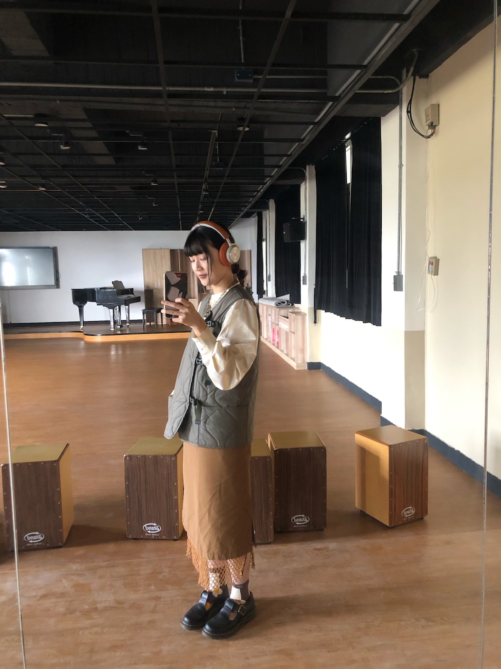 ブラック系のその他シューズ、オレンジ系のスカート、グリーン系のダウンベストを着用したレディースの冬コーディネートの3枚目の写真