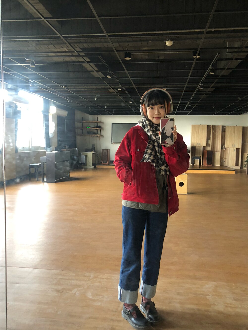 レッド系のデニムジャケット、ブラック系のその他シューズ、オレンジ系のヘッドフォン/イヤホンを着用したレディースの冬コーディネートの2枚目の写真