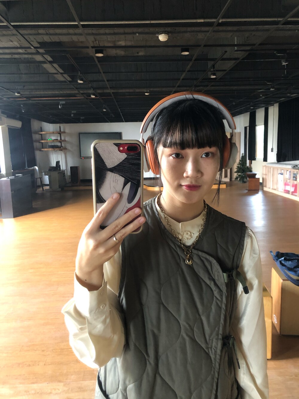 ブラック系のその他シューズ、オレンジ系のスカート、グリーン系のダウンベストを着用したレディースの冬コーディネートの4枚目の写真