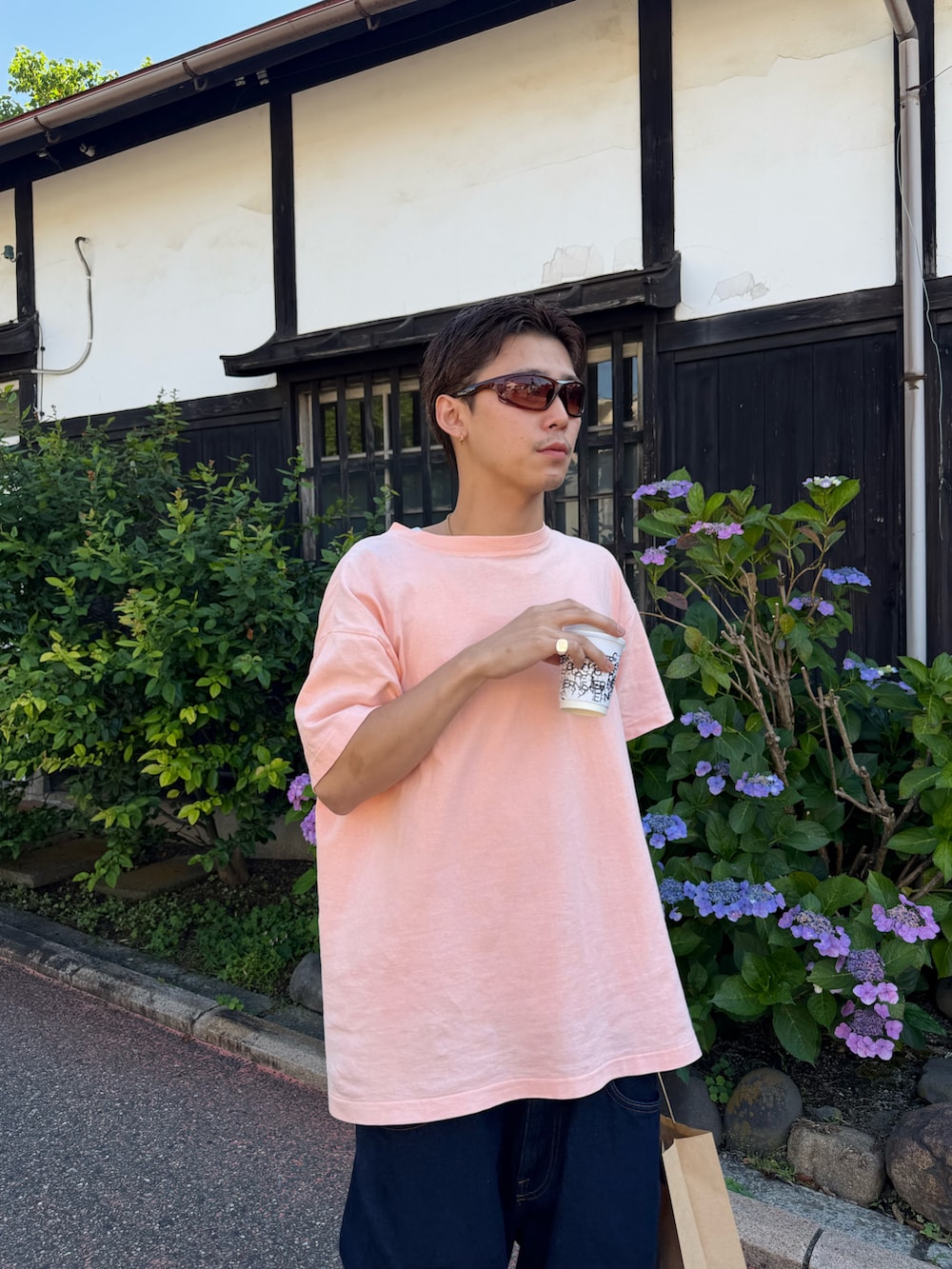ブルー系のデニムパンツ、ピンク系のTシャツ/カットソー、ブルー系のスニーカーを着用したメンズの夏コーディネートの3枚目の写真