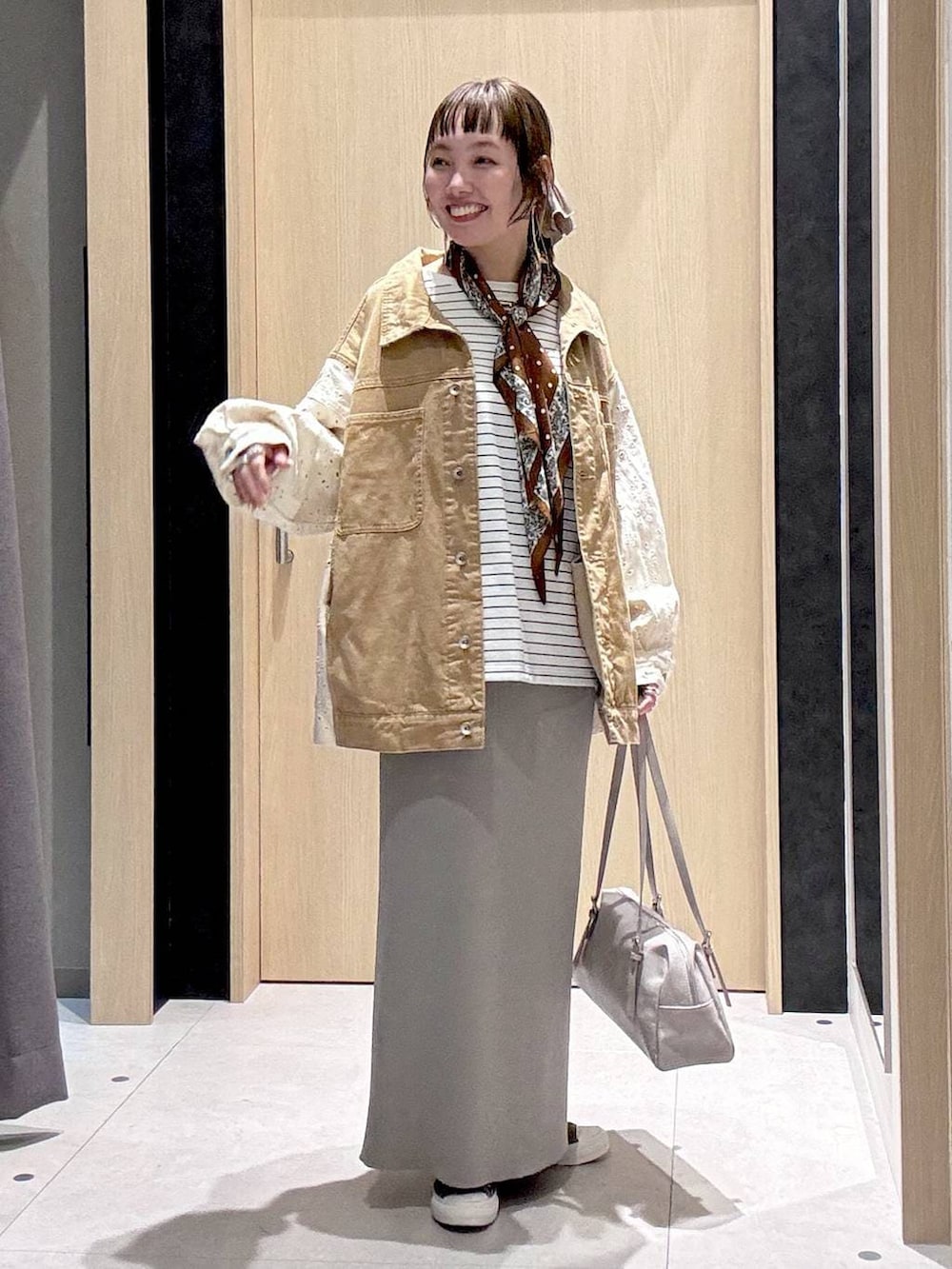 グレー系のスカート、イエロー系のスニーカー、グレー系のボストンバッグを着用したレディースの冬コーディネートの2枚目の写真