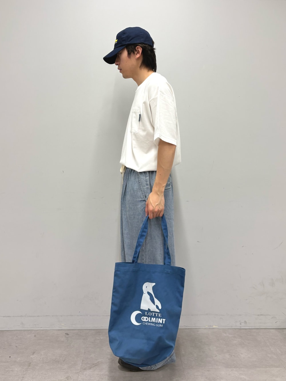 ホワイト系のTシャツ/カットソー、ブルー系のデニムパンツ、ブルー系のトートバッグを着用したメンズの春コーディネートの2枚目の写真