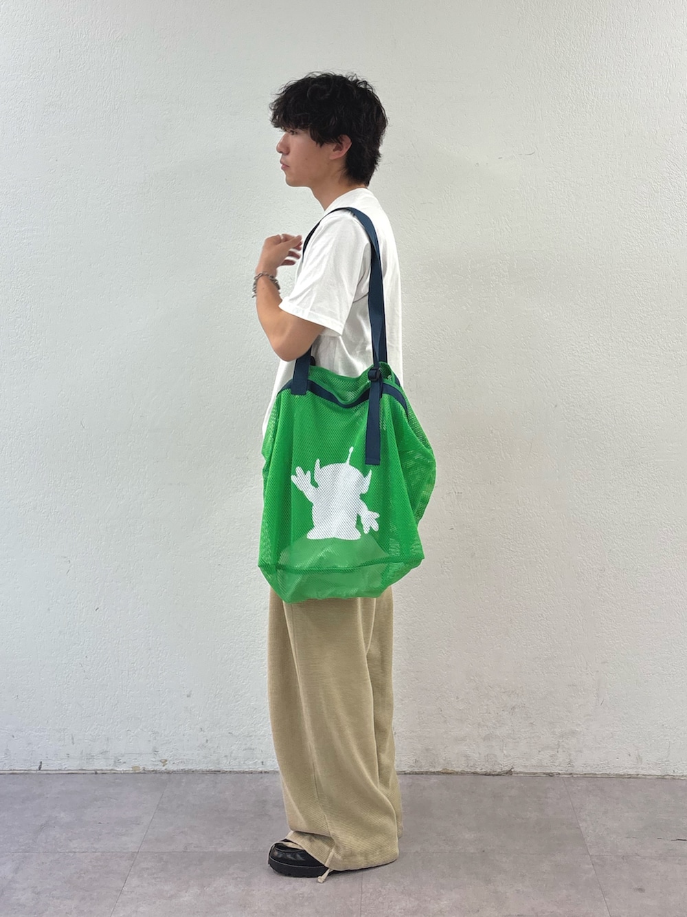 ホワイト系のTシャツ/カットソー、グリーン系のトートバッグ、ベージュ系のスウェットパンツを着用したメンズの春コーディネートの2枚目の写真