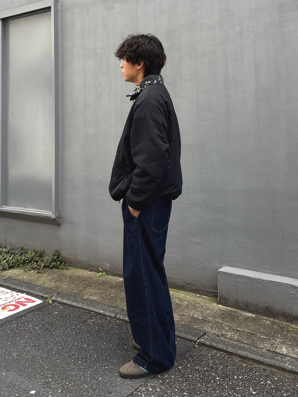 ブラック系のブルゾン、ブルー系のデニムパンツを着用したメンズの秋コーディネートの2枚目の写真