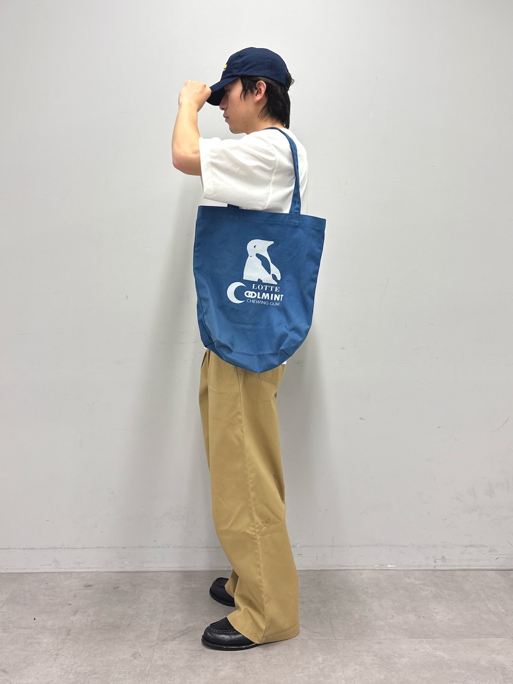 ホワイト系のTシャツ/カットソー、ブルー系のトートバッグ、ベージュ系のデニムパンツを着用したメンズの春コーディネートの2枚目の写真