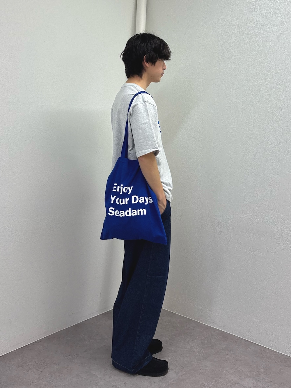 グレー系のTシャツ/カットソー、ブルー系のトートバッグ、ブルー系のデニムパンツを着用したメンズの春コーディネートの2枚目の写真