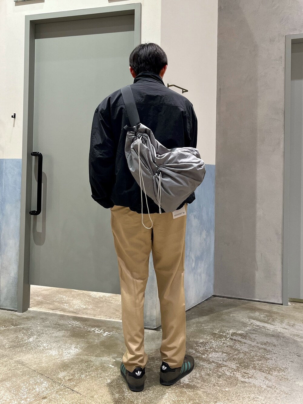 グレー系のスニーカー、ベージュ系のデニムパンツ、ブラック系のナイロンジャケットを着用したメンズの春コーディネートの2枚目の写真