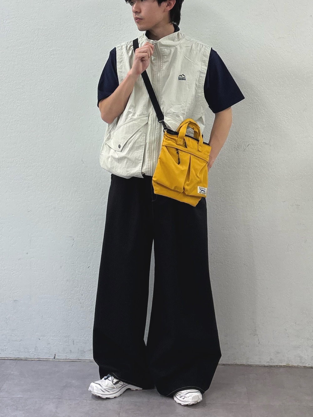 ブラック系のTシャツ/カットソー、グレー系のベスト、イエロー系のショルダーバッグを着用したメンズの春コーディネートの2枚目の写真