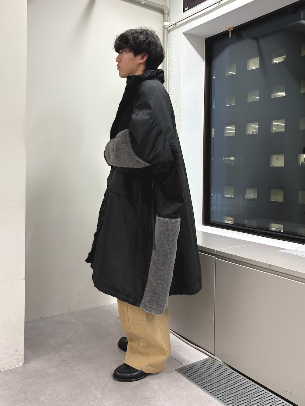 ブラック系のモッズコート、グレー系のニット/セーター、ベージュ系のカーゴパンツを着用したメンズの冬コーディネートの2枚目の写真