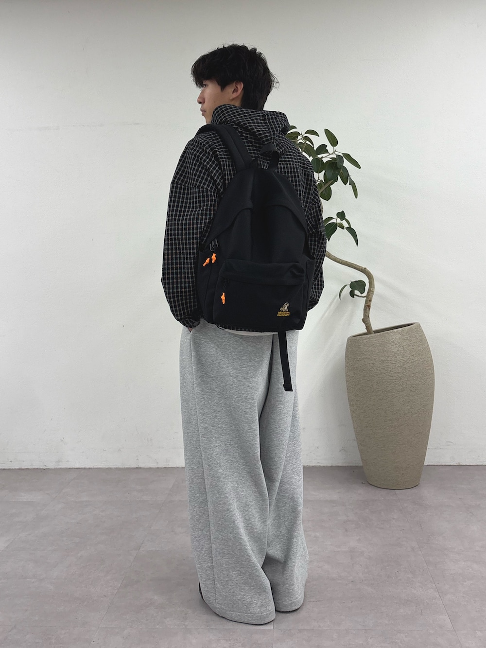 ブラック系のパーカー、ブラック系のバックパック/リュック、グレー系のその他パンツを着用したメンズの春コーディネートの2枚目の写真