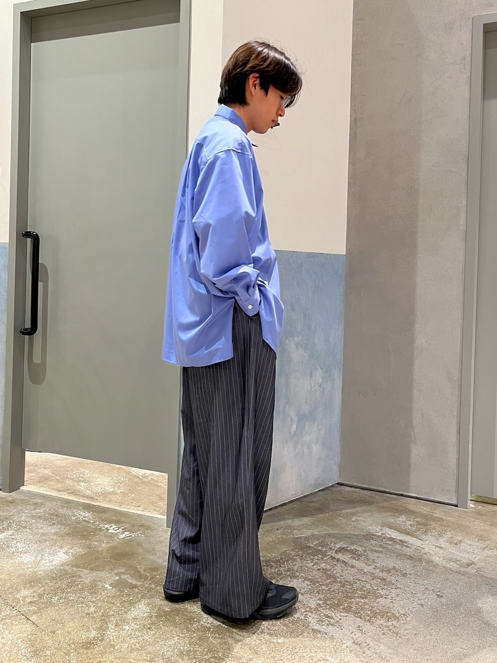 ブルー系のシャツ/ブラウス、グレー系のスラックス、ブラック系のスニーカーを着用したメンズの春コーディネートの2枚目の写真