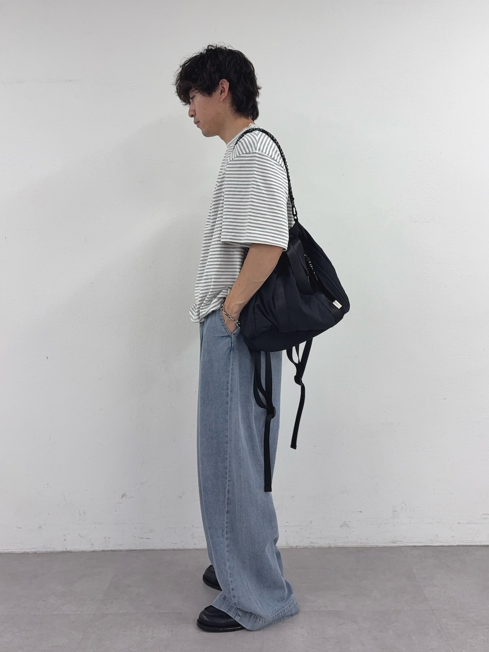 グレー系のTシャツ/カットソー、ブラック系のトートバッグ、ブルー系のデニムパンツを着用したメンズの春コーディネートの2枚目の写真