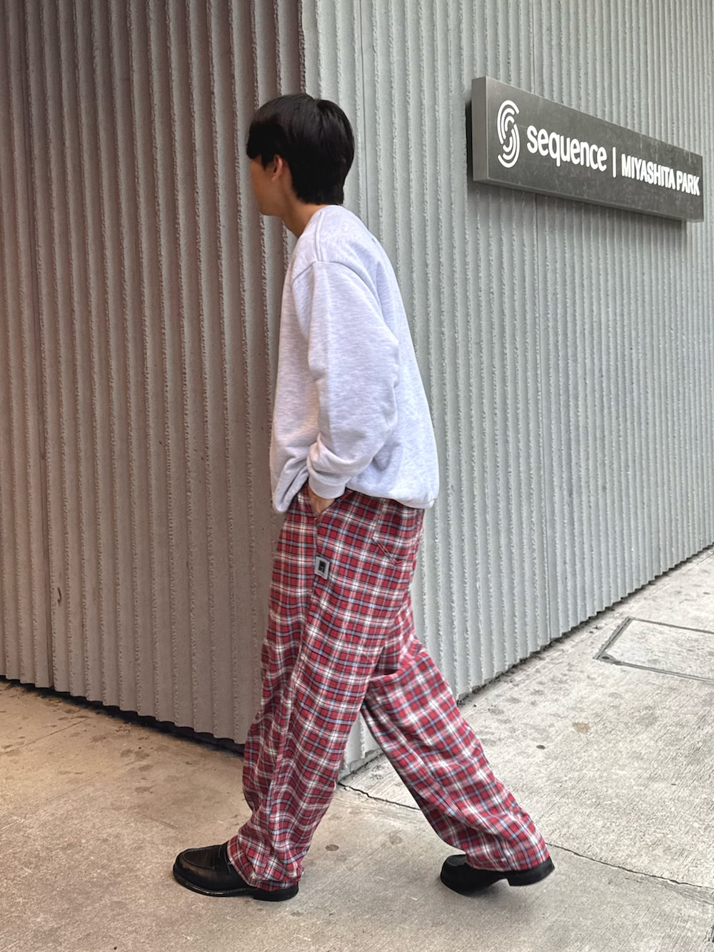 グレー系のスウェット、レッド系のスラックスを着用したメンズの秋コーディネートの2枚目の写真