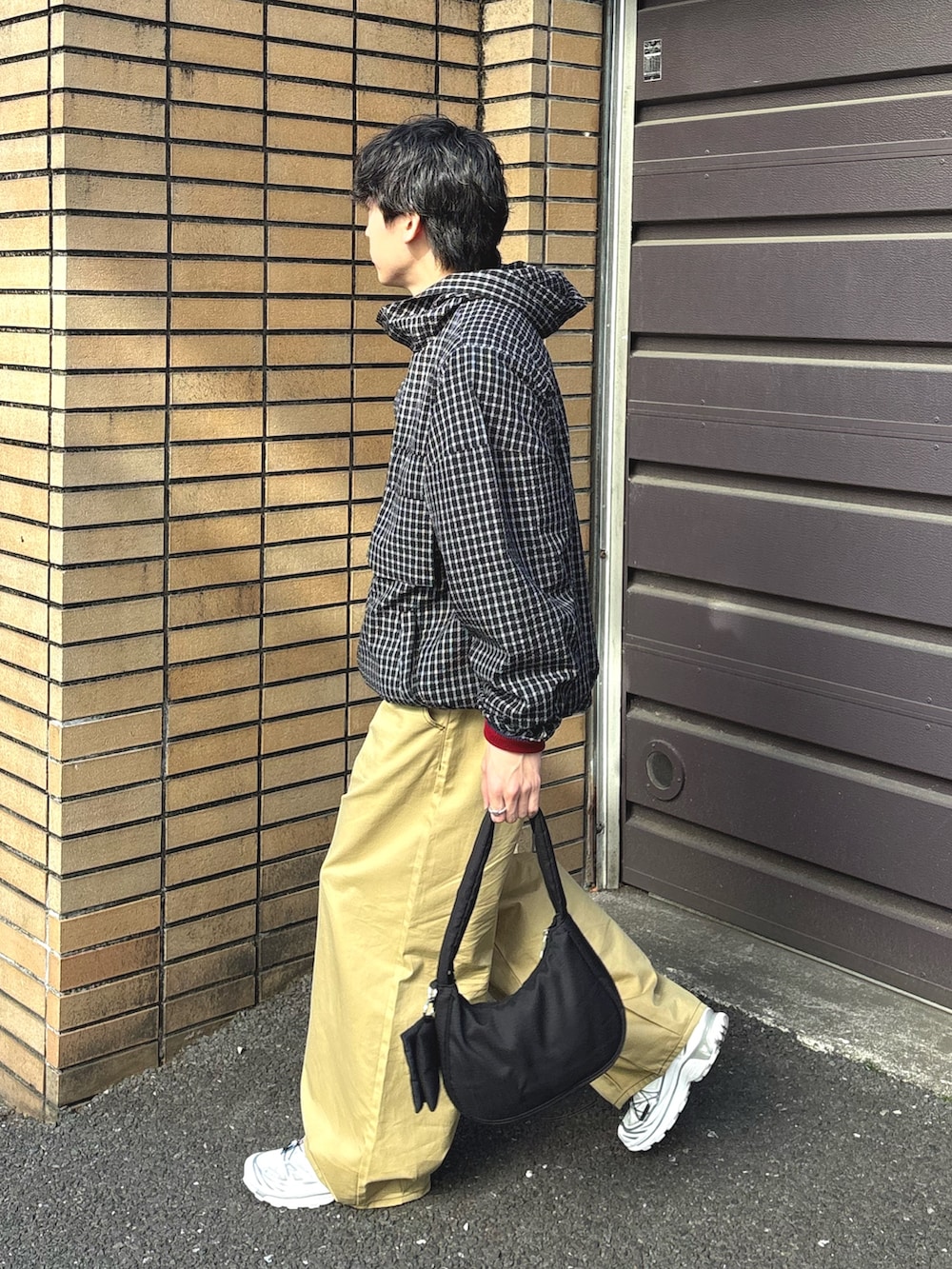 ブラック系のパーカー、ブルー系のニット/セーター、ベージュ系のチノパンツを着用したメンズの春コーディネートの2枚目の写真