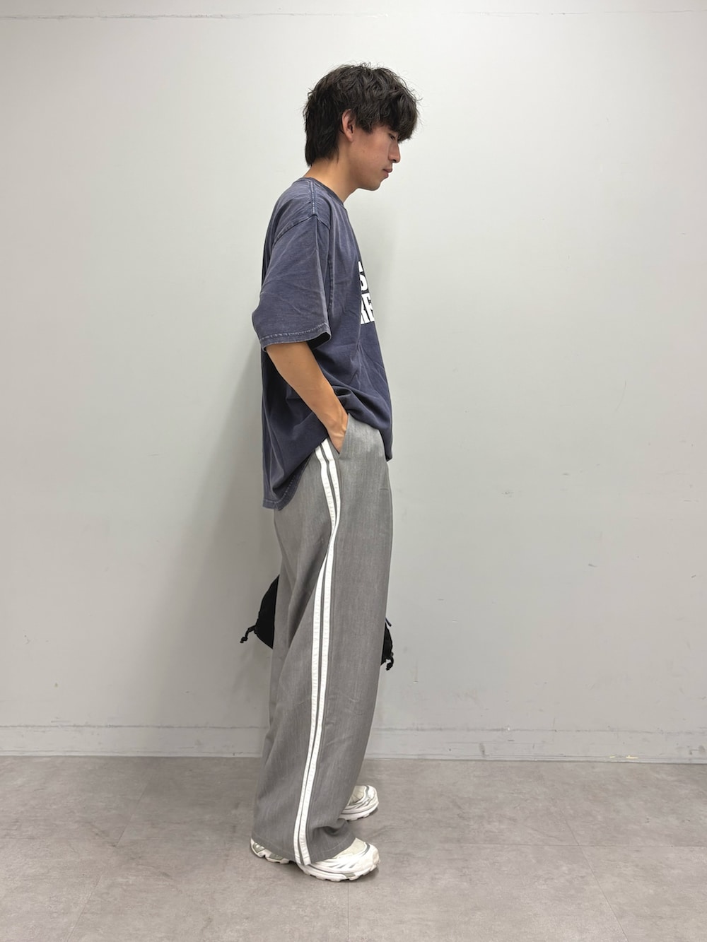 ブルー系のTシャツ/カットソー、グレー系のスラックス、ブラック系のトートバッグを着用したメンズの夏コーディネートの2枚目の写真