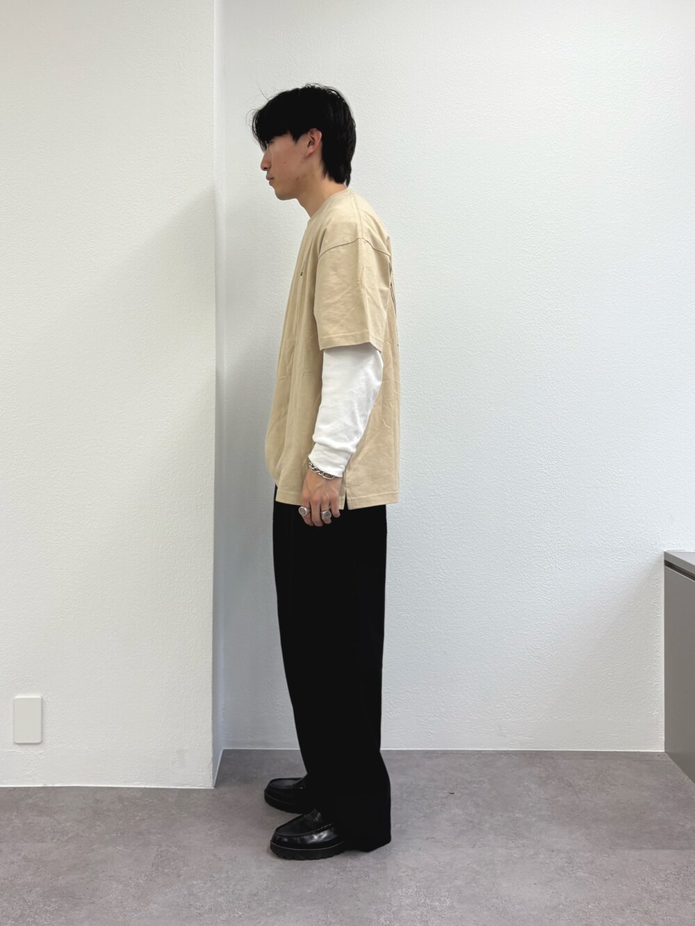 ベージュ系のTシャツ/カットソー、ブラック系のスラックスを着用したメンズの春コーディネートの2枚目の写真