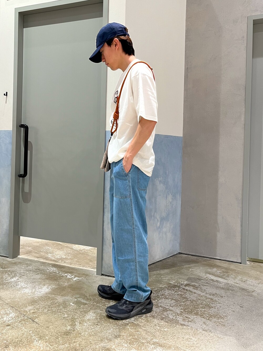 ブルー系のデニムパンツ、ブラック系のスニーカー、ブラック系のショルダーバッグを着用したメンズの夏コーディネートの2枚目の写真