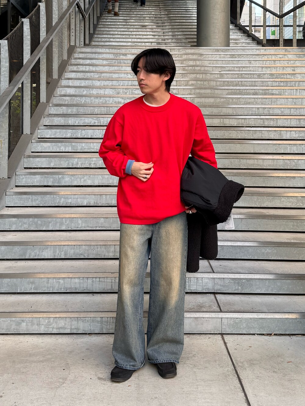 レッド系のニット/セーター、ブラック系のブルゾン、ブルー系のデニムパンツを着用したメンズの冬コーディネートの2枚目の写真