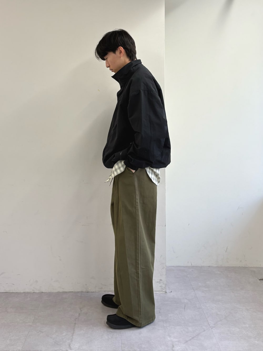 グリーン系のスラックス、ブラック系のナイロンジャケット、ホワイト系のシャツ/ブラウスを着用したメンズの春コーディネートの2枚目の写真