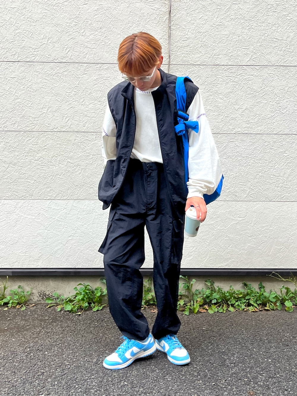 ブルー系のスニーカー、ブラック系のベスト、ホワイト系のTシャツ/カットソーを着用したメンズの秋コーディネートの2枚目の写真