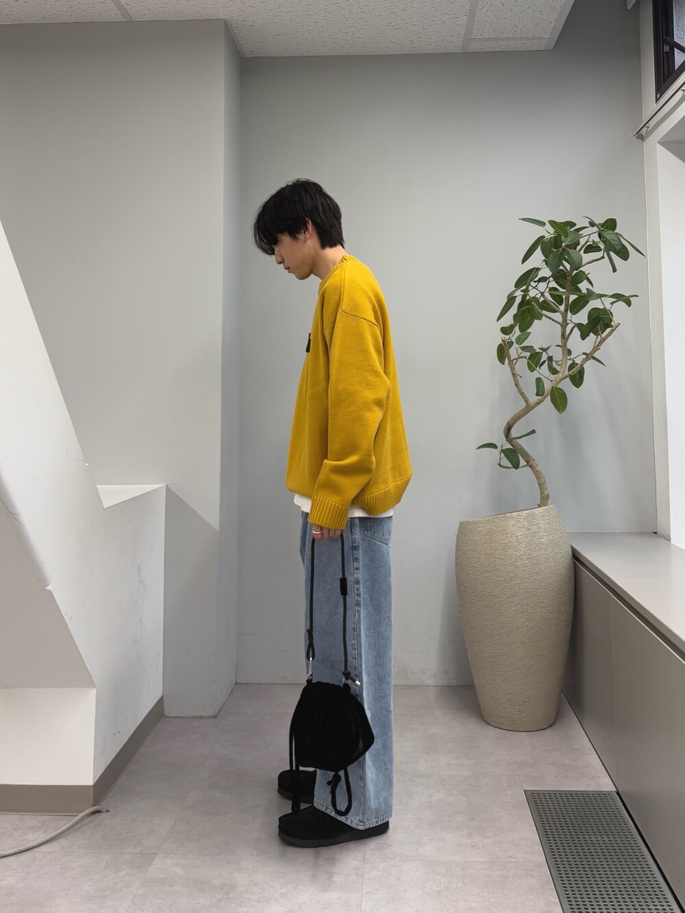 イエロー系のニット/セーター、ブルー系のデニムパンツ、ブラック系のショルダーバッグを着用したメンズの春コーディネートの2枚目の写真