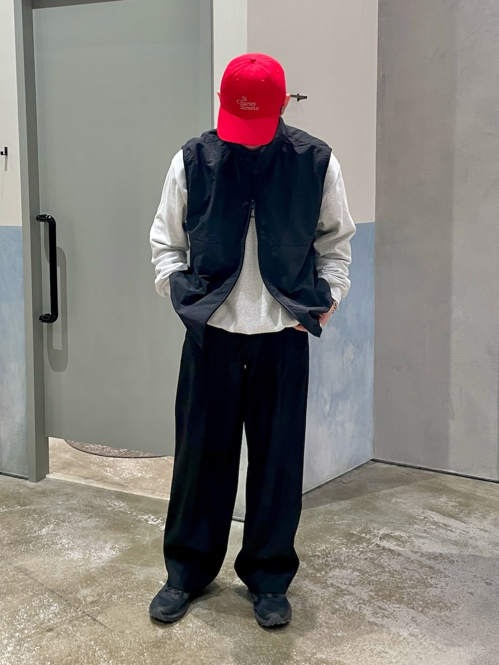 ブラック系のスニーカー、ブラック系のスラックス、ブラック系のベストを着用したメンズの春コーディネートの2枚目の写真