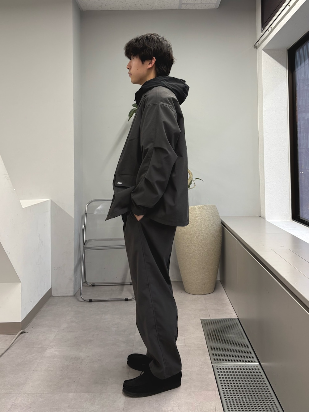 グレー系のテーラードジャケット、ブラック系のマウンテンパーカー、グレー系のスラックスを着用したメンズの春コーディネートの2枚目の写真