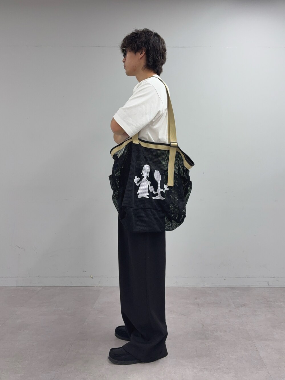 ホワイト系のTシャツ/カットソー、ブラック系のスラックス、ブラック系のトートバッグを着用したメンズの夏コーディネートの2枚目の写真