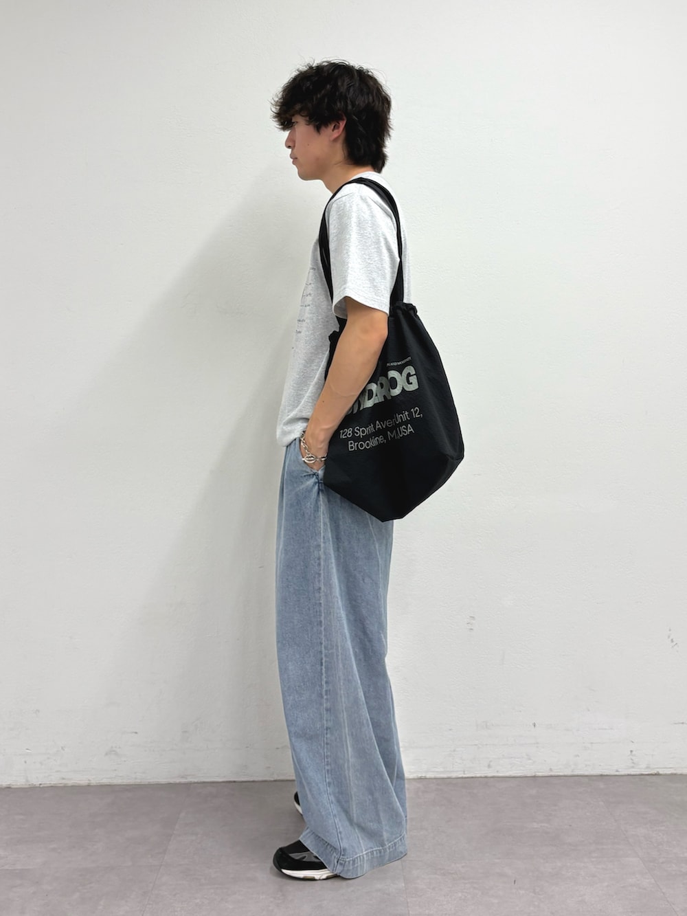 グレー系のTシャツ/カットソー、ブラック系のトートバッグ、ブルー系のデニムパンツを着用したメンズの夏コーディネートの2枚目の写真
