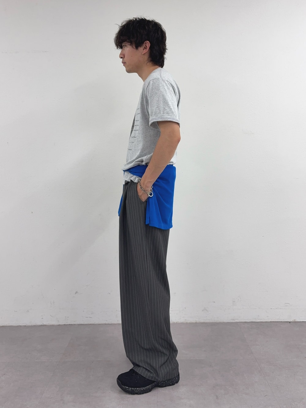 グレー系のTシャツ/カットソー、ブルー系のTシャツ/カットソー、グレー系のスラックスを着用したメンズの春コーディネートの2枚目の写真