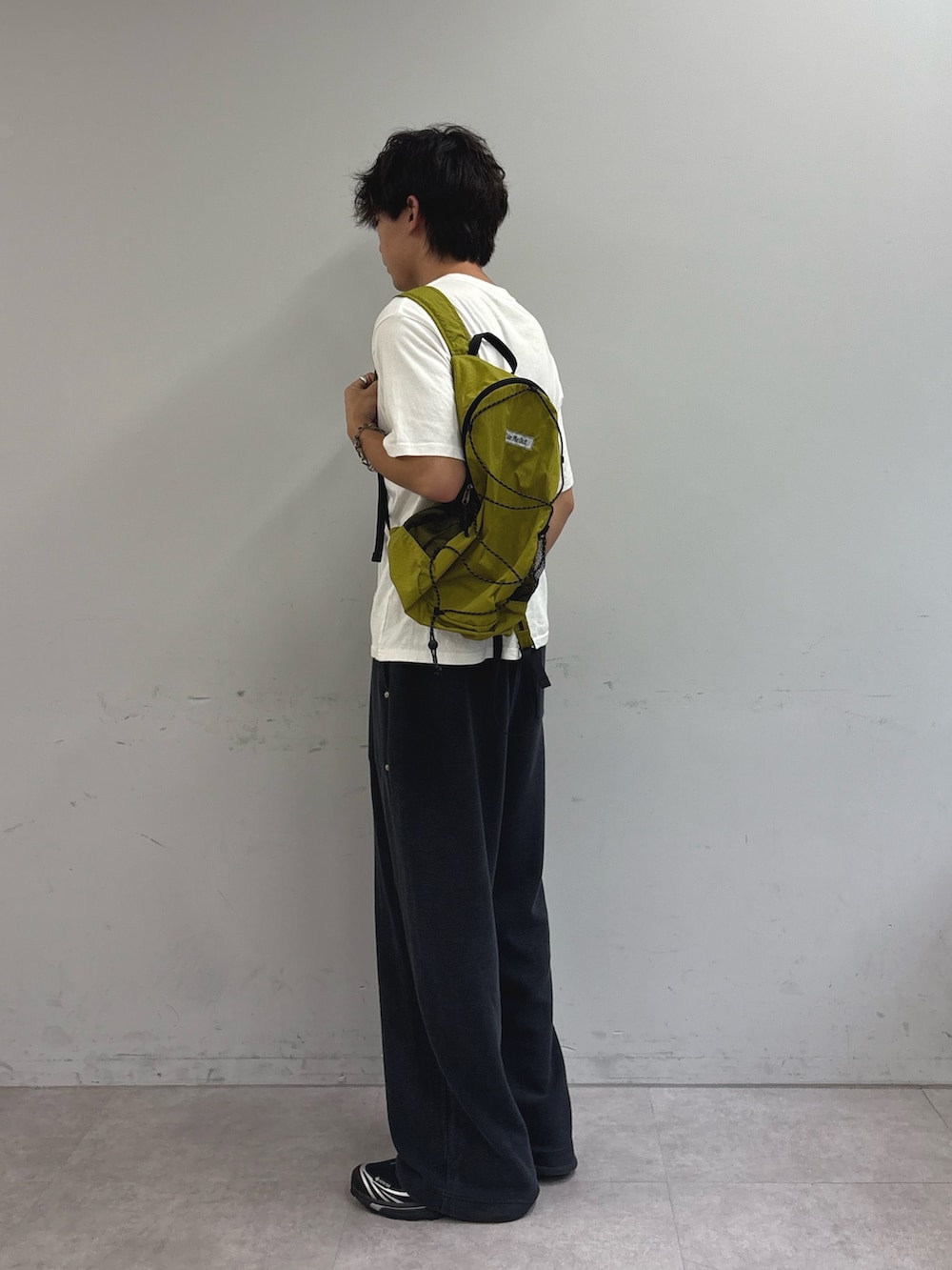 ホワイト系のTシャツ/カットソー、グリーン系のバックパック/リュック、ブラック系のスウェットパンツを着用したメンズの秋コーディネートの2枚目の写真