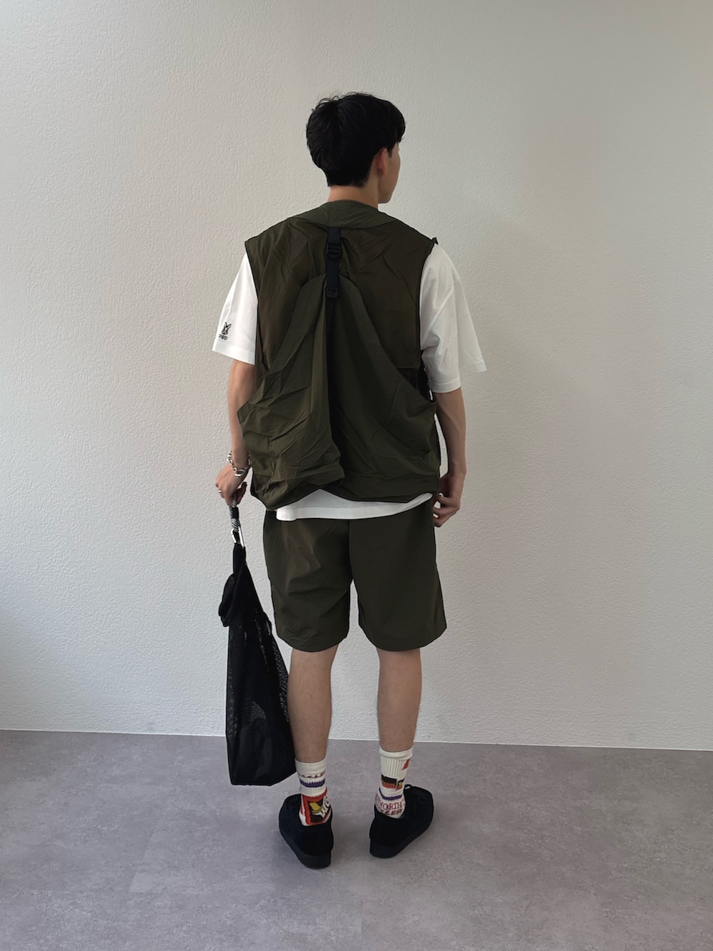 ホワイト系のTシャツ/カットソー、グリーン系のベスト、ブラック系のトートバッグを着用したメンズの春コーディネートの3枚目の写真