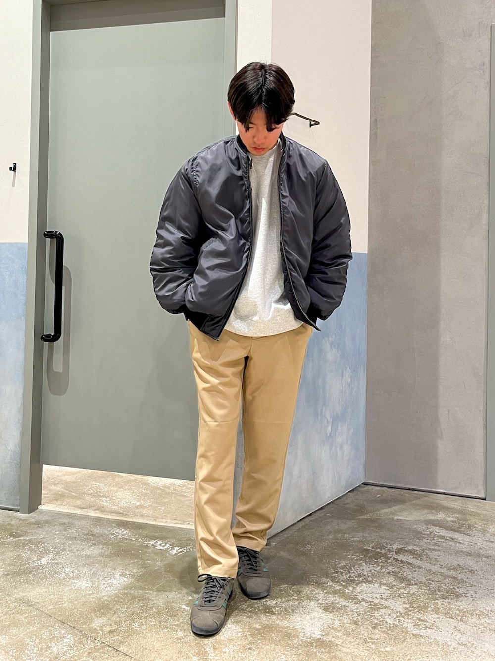 グレー系のスウェット、ブラック系のMA-1、ベージュ系のデニムパンツを着用したメンズの春コーディネートの2枚目の写真