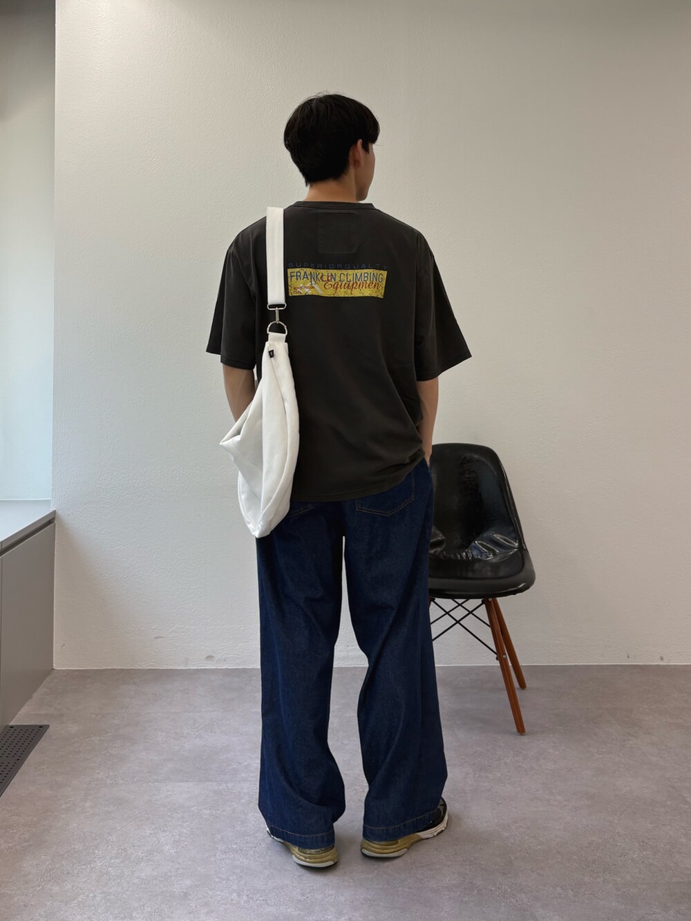 ブラック系のTシャツ/カットソー、ホワイト系のショルダーバッグ、ブルー系のデニムパンツを着用したメンズの夏コーディネートの2枚目の写真