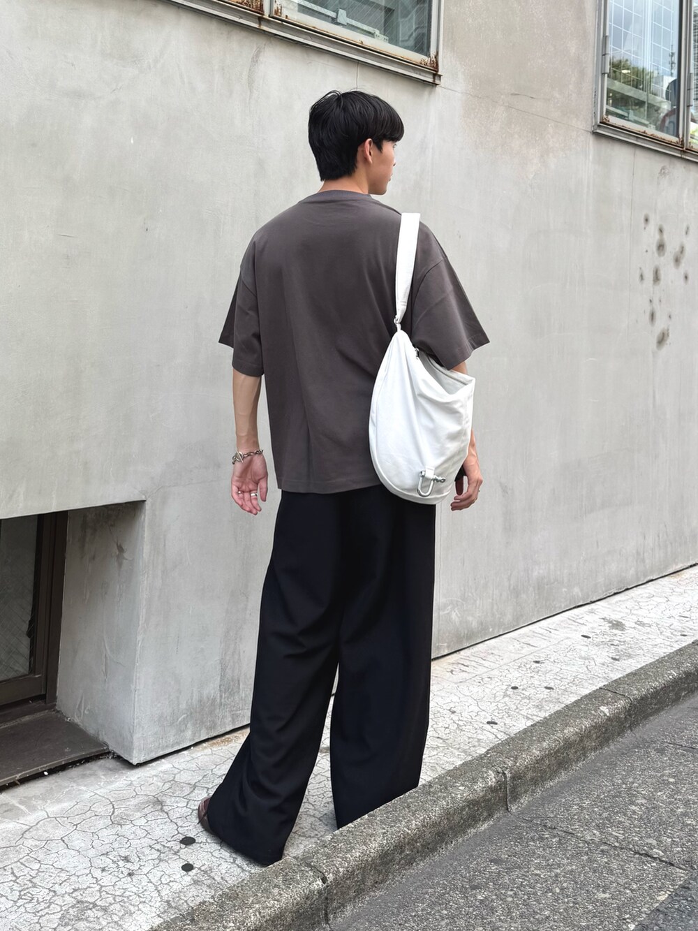 グレー系のTシャツ/カットソー、ホワイト系のショルダーバッグ、ブラック系のスラックスを着用したメンズの夏コーディネートの2枚目の写真